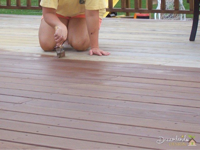 Staining the deck with the playset project looming in the background Staining the deck with the playset project looming in the background