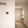 Wall-mounted home thermostat and HVAC air vent in a quiet residential hallway