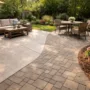 concrete vs pavers patio comparison with curved layout in a landscaped backyard