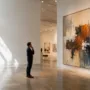 Homeowner viewing a large abstract painting in a contemporary art gallery before choosing wall art for a modern home.