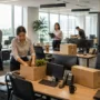 Employees preparing a commercial office move by packing workstations, labeling equipment, and organizing IT infrastructure before relocation