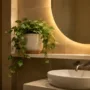 A realistic artificial trailing plant in a stoneware pot styled on a floating shelf in a modern windowless bathroom
