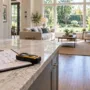 Architectural blueprints and a digital measuring tool on a kitchen island during a property inspection walk-through