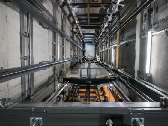 Close-up of heavy-duty industrial lift components and steel guide rails inside a commercial elevator hoistway