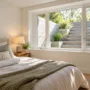 A large modern casement egress window letting bright natural sunlight into a finished basement bedroom