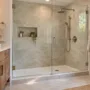 A modern walk-in shower with custom tile and frameless glass that replaced a standard residential bathtub.